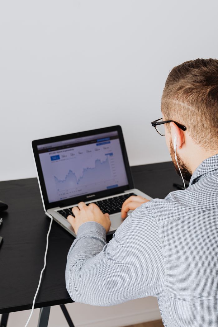home-img A man uses a laptop indoors to analyze stock market trends graph on screen.